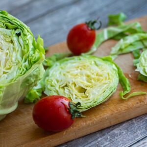 Fresh washed iceberg lettuce and tomatoes on cutting board